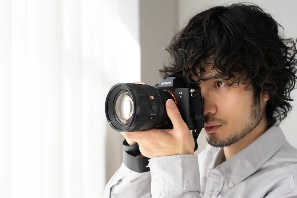 Fotograf z aparatem Sony przy oknie